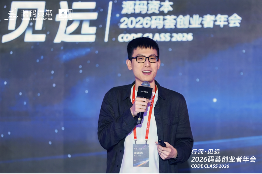 图片展示的是2026码荟创业者年会现场，一位身着黑色外套、白色T恤的男子正在台上演讲。他手持麦克风，另一只手握着遥控器，佩戴着红色挂绳的证件。背景大屏幕上显示“源码资本 2026码荟创业者年会 CODE CLASS 2026”字样，左侧还有“见远”标识。该图片与文档中胡渊鸣为2026码荟创业者年会准备的CEO视角实践干货内容相关，呈现了演讲场景。