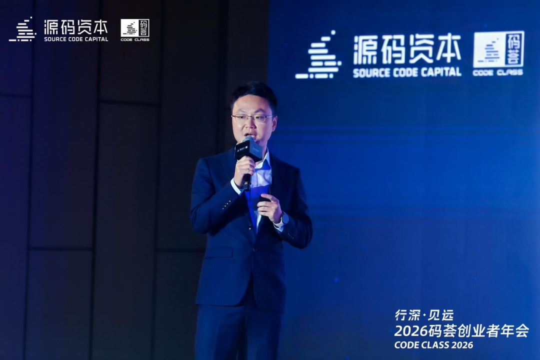这是源码资本创始人张洵在2026码荟创业者年会上进行分享的现场画面，他身着深蓝色西装，手持麦克风，神情专注。背景板与现场展板上均带有源码资本的标识，右下角标注了“行深·贝远 2026码荟创业者年会 CODE CLASS 2026”的字样，该场景对应文档中张洵关于投资与增长话题的分享环节，是其分享内容的现场呈现。