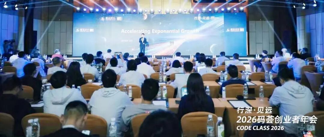 图片展示的是2026码荟创业者年会现场。舞台背景大屏幕上显示“Accelerating Exponential Growth”及“行深·贝远”字样。台上有一位男士正在演讲。会场内，观众席上坐满了人，大家或专注听讲，或低头记录，气氛庄重。会场布置整齐，桌上有水瓶等物品。图片与上下文紧密相关，直观呈现了文章中提及的2026码荟创业者年会场景，为读者提供了活动的视觉参考。